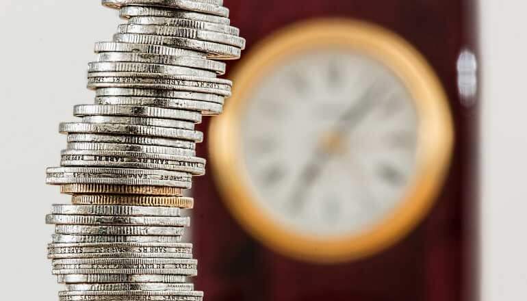 stack of coins with clock in background