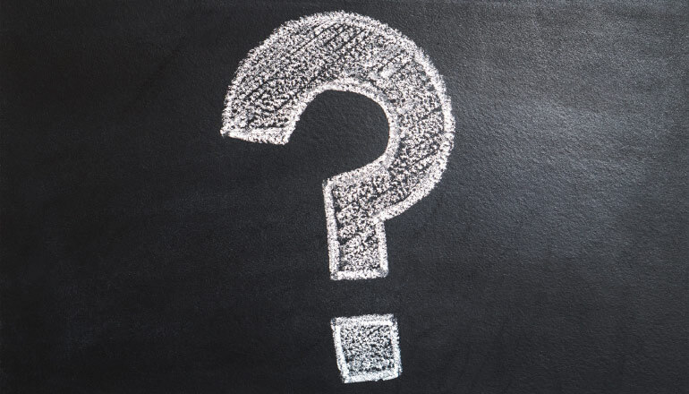 Large question mark drawn with white chalk on a black chalkboard