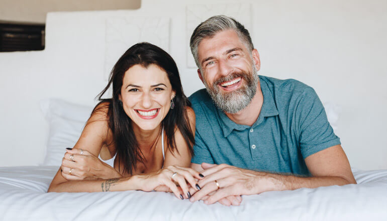 Husband and wife with great oral health smile as they hold hands