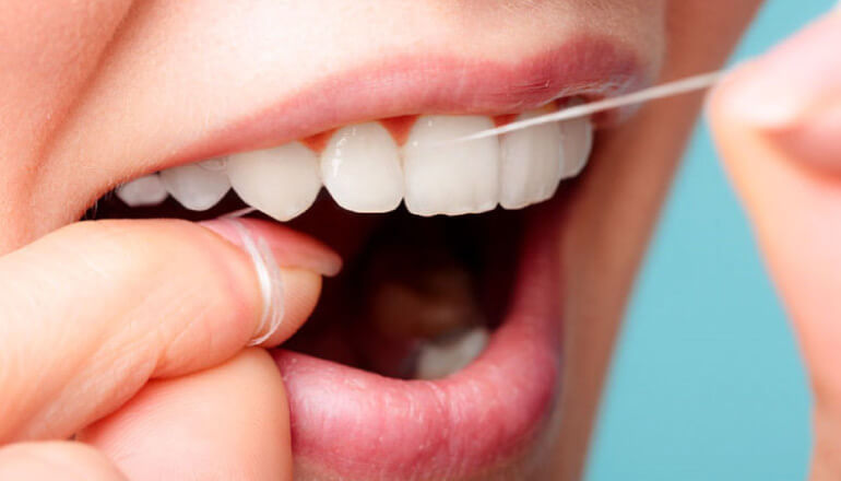 closeup of a woman flossing her teeth