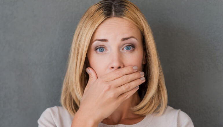 woman covering her mouth with her hand to hide yellow teeth