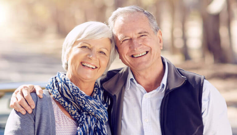 senior couple hug and smile after getting dental crowns