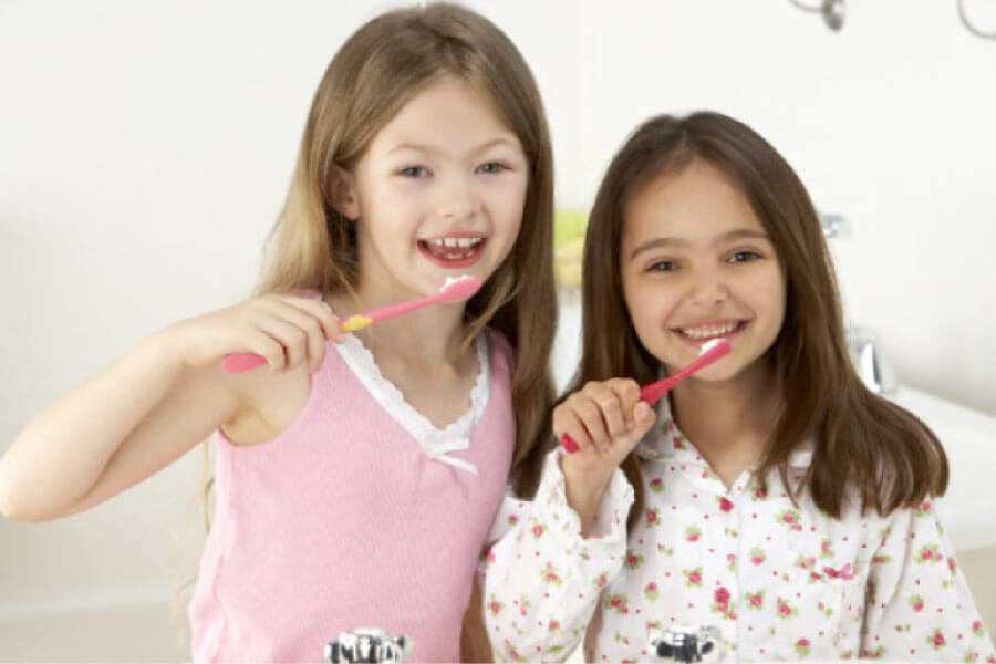 two young girls brushing their teeth