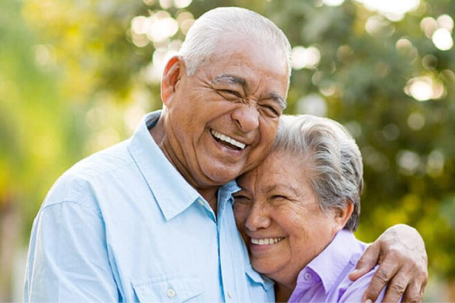 senior couple hug and smile after learning about the benefits of dental implants