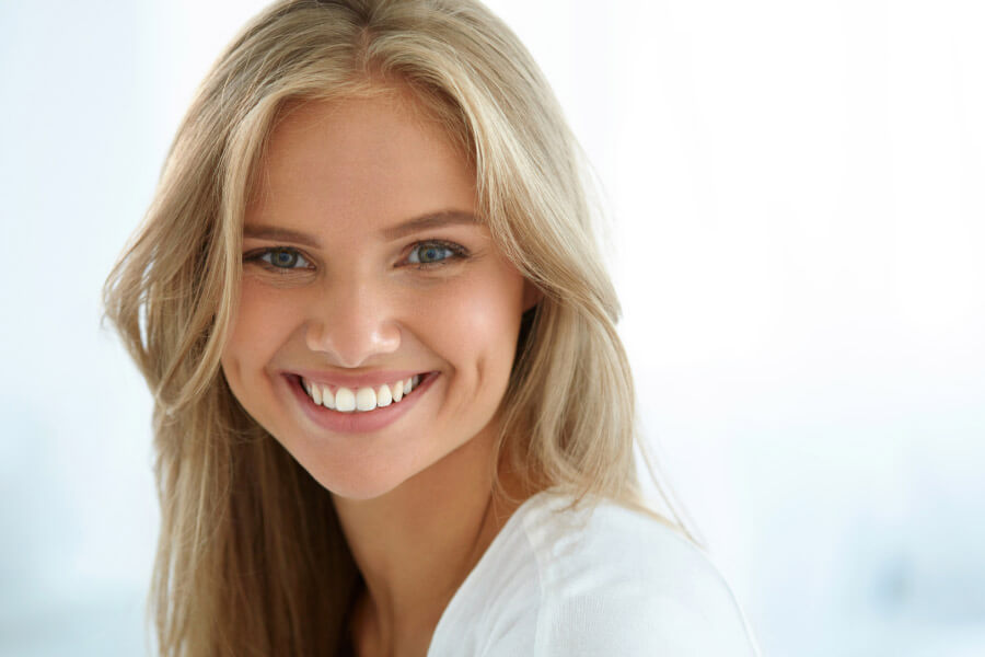 young woman flashes a bright white smile after professional teeth whitening treatment