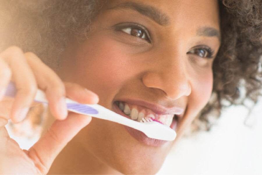 young woman brushes her teeth to combat receding gums