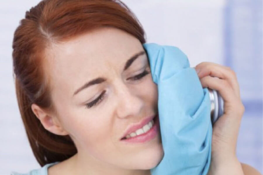 woman holds an ice pack to her face after a dental emergency
