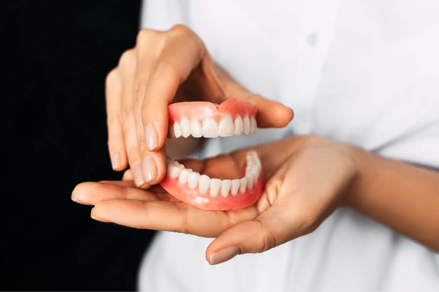 two hands holding a set of dentures