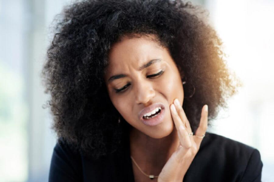 woman holds her cheek in pain with a dental emergency