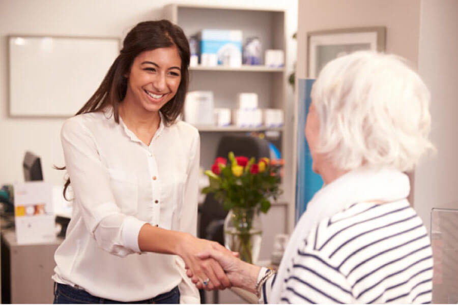 dental assistant greets a senior woman as a new patient