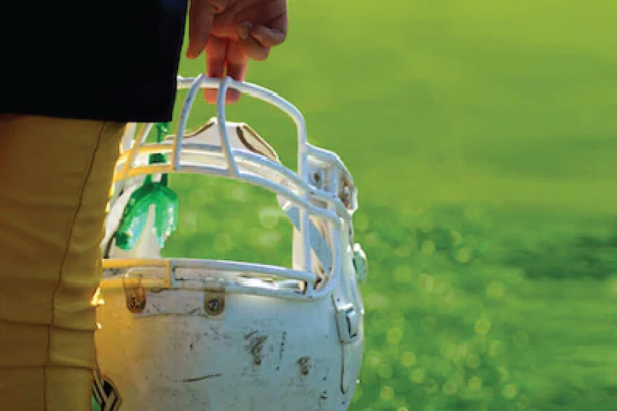 athletic mouthguard hanging off a football helmet being carried with two fingers