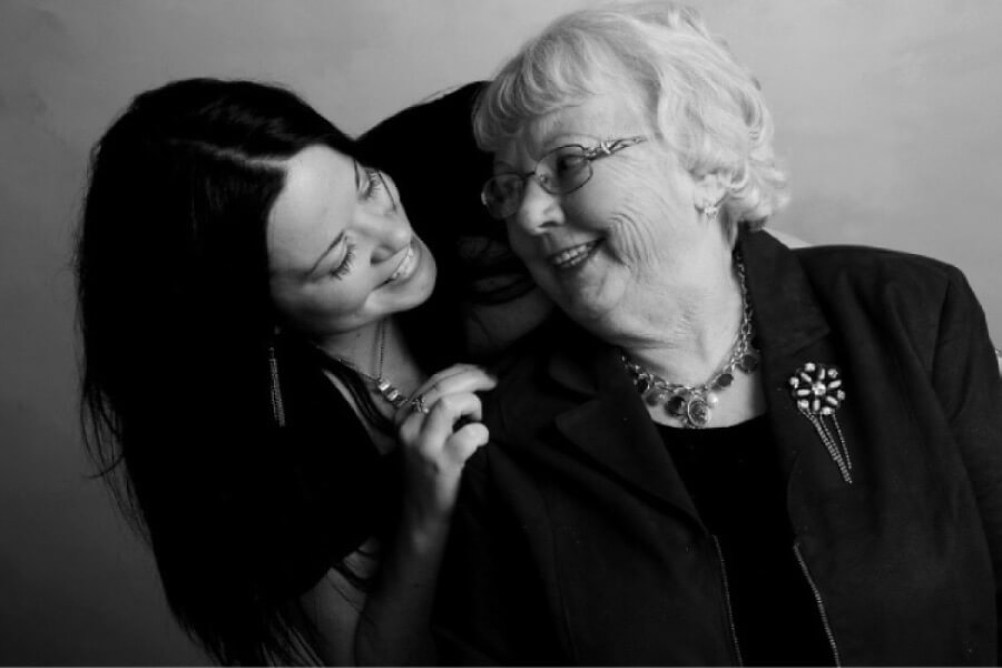 adult granddaughter hugs and smiles at her grandmother.